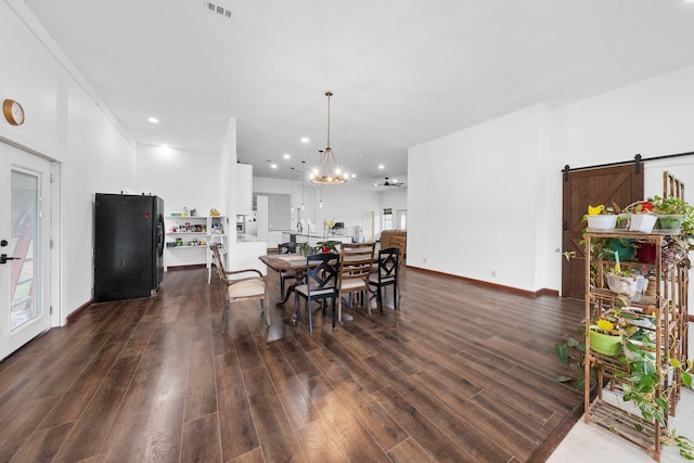 dining area with a barn door, a chandelier, dark wood-type flooring, and recessed lighting