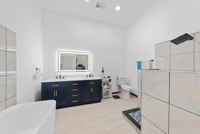 full bath featuring a sink, double vanity, a freestanding bath, toilet, and visible vents