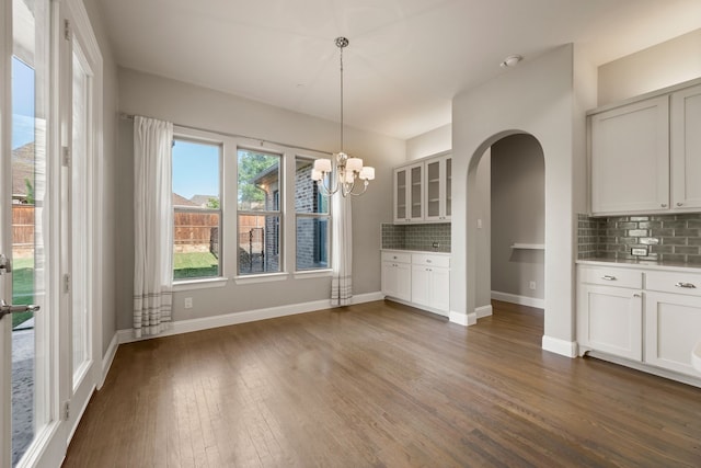 1001 Broadmoor Way, Roanoke, TX 76262 - unfurnished dining area featuring baseboards, dark wood-style floors, arched walkways, and a notable chandelier