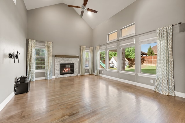1001 Broadmoor Way, Roanoke, TX 76262 - unfurnished living room with high vaulted ceiling, a stone fireplace, wood finished floors, ceiling fan, and baseboards