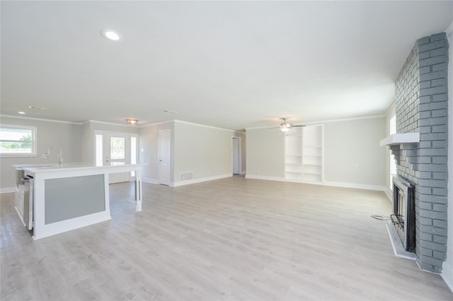 unfurnished living room featuring baseboards, ornamental molding, a brick fireplace, and visible vents