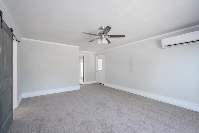 carpeted spare room featuring a barn door, a ceiling fan, baseboards, a wall mounted AC, and ornamental molding