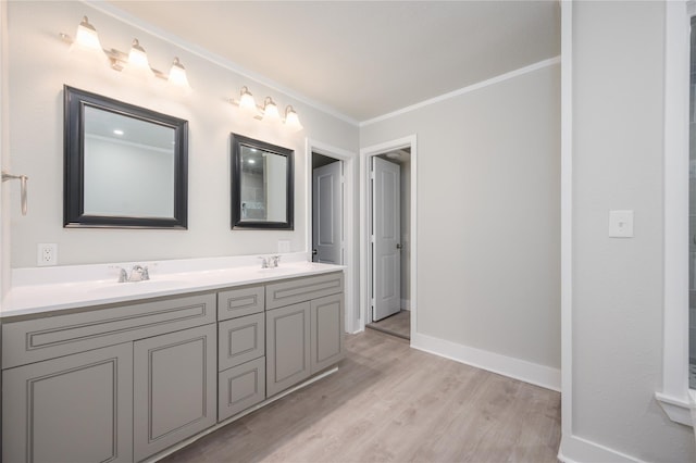 bathroom featuring crown molding, double vanity, a sink, and wood finished floors
