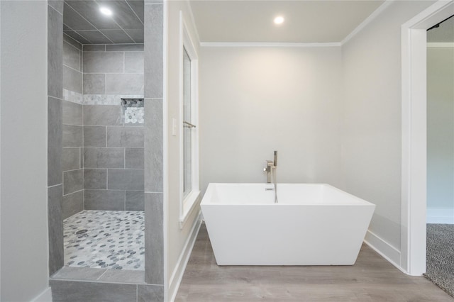 bathroom featuring a soaking tub, baseboards, a tile shower, and wood finished floors