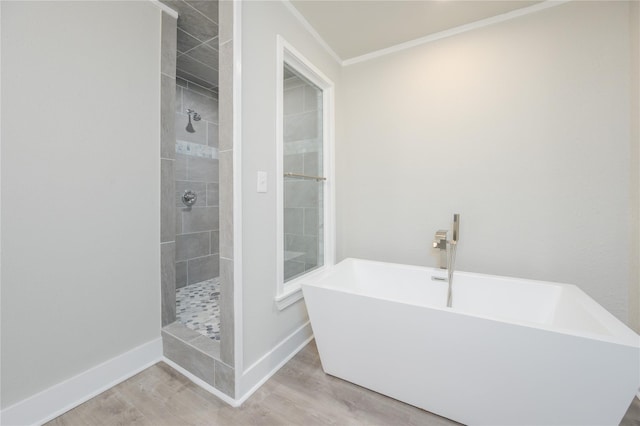 full bathroom with crown molding, a freestanding tub, a tile shower, wood finished floors, and baseboards
