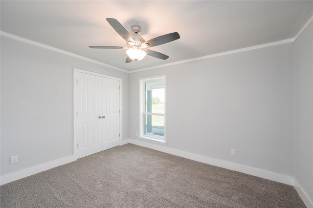 unfurnished bedroom featuring crown molding, baseboards, carpet, and a closet