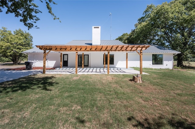 rear view of house with a yard, a chimney, metal roof, and a patio area