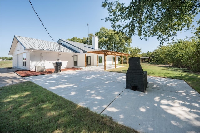 back of property with a chimney, metal roof, a lawn, a patio area, and a pergola