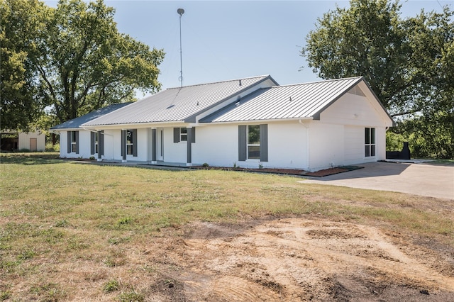 back of property with a standing seam roof, covered porch, a lawn, and metal roof