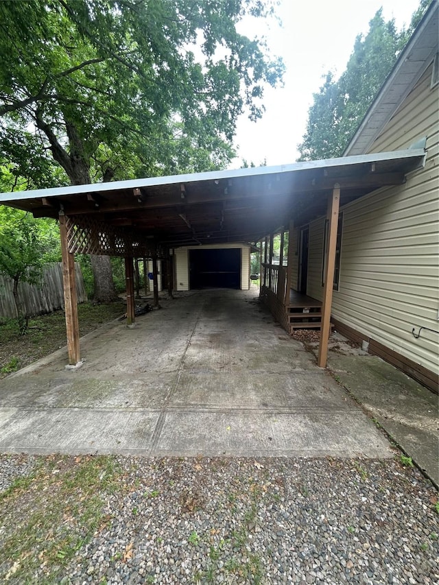 view of parking with fence, a carport, and gravel driveway
