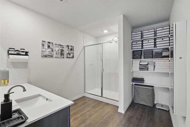 bathroom with wood finished floors, baseboards, a stall shower, and a sink