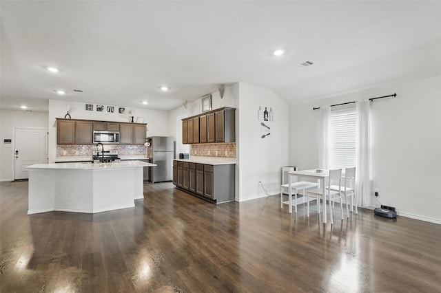kitchen featuring decorative backsplash, appliances with stainless steel finishes, visible vents, light countertops, and dark wood-style flooring