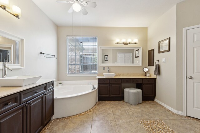 full bathroom with two vanities, a garden tub, a ceiling fan, and a sink