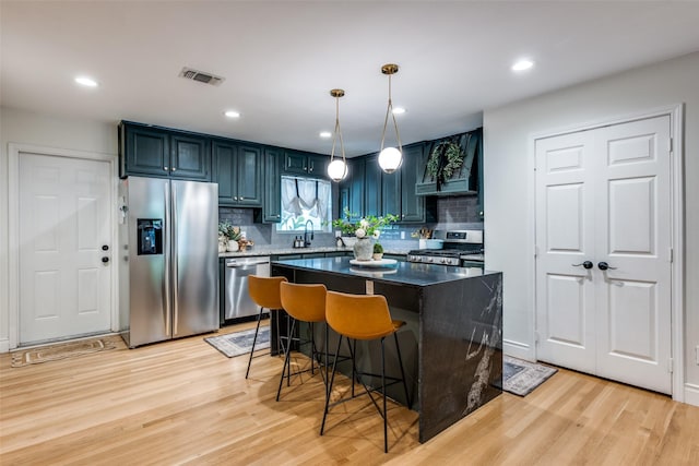 kitchen featuring light wood-type flooring, visible vents, appliances with stainless steel finishes, and premium range hood