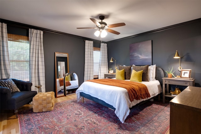 bedroom with dark wood-style flooring, crown molding, a ceiling fan, and multiple windows