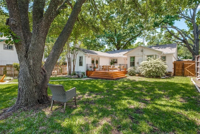 rear view of property featuring a fenced backyard, a wooden deck, and a yard