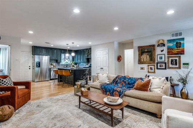 living room featuring recessed lighting, light wood-type flooring, and visible vents