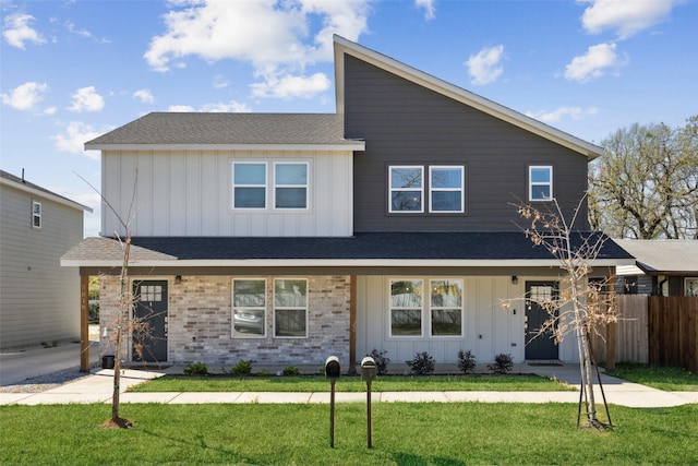 view of front facade with fence, board and batten siding, a shingled roof, and a front yard