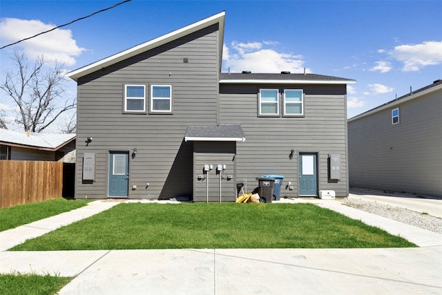 rear view of property with fence and a yard