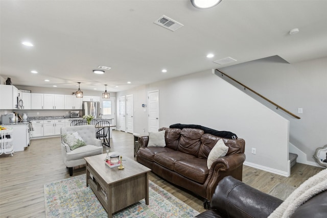 living room featuring light wood-style flooring, baseboards, visible vents, recessed lighting, and stairway