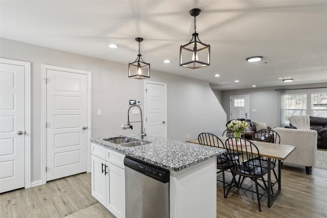 kitchen featuring light wood finished floors, dishwasher, a sink, pendant lighting, and open floor plan