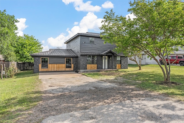 view of front of home with concrete driveway, a front lawn, metal roof, and fence