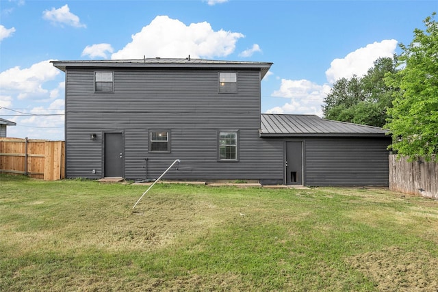 rear view of property with a lawn, fence, and metal roof