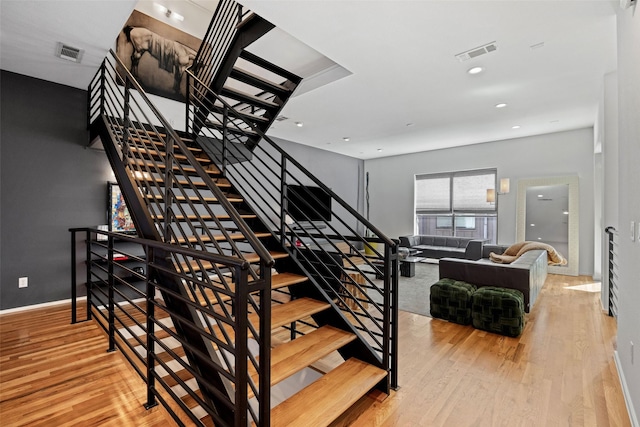 stairway with baseboards, wood finished floors, visible vents, and recessed lighting