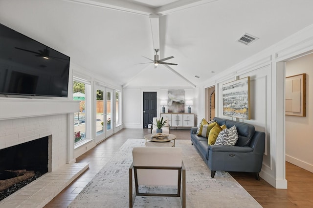 living room featuring visible vents, wood finished floors, a fireplace, and ceiling fan