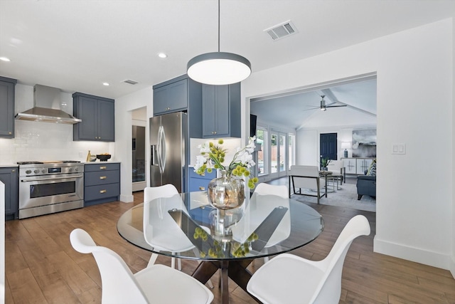 dining area with vaulted ceiling, wood finished floors, visible vents, and a ceiling fan