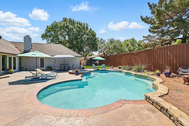 view of pool with fence, a pool with connected hot tub, and a patio