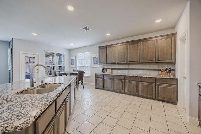 kitchen featuring decorative backsplash, visible vents, a sink, baseboards, and light tile patterned floors