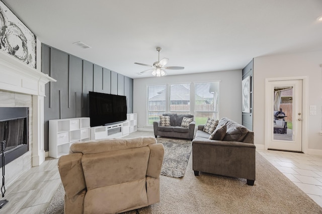 living area with a ceiling fan, visible vents, a fireplace, light tile patterned floors, and baseboards