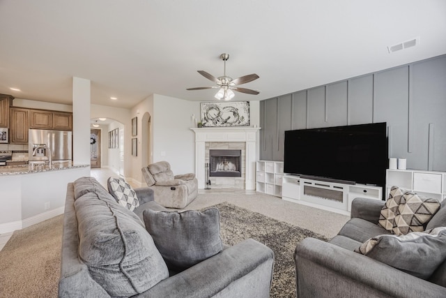living area with ceiling fan, a fireplace, arched walkways, recessed lighting, and visible vents