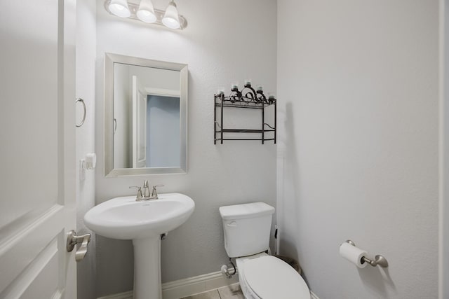 half bath featuring baseboards, tile patterned floors, and toilet