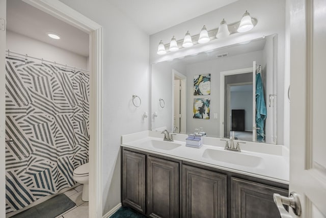 full bathroom featuring a sink, tile patterned flooring, toilet, and double vanity