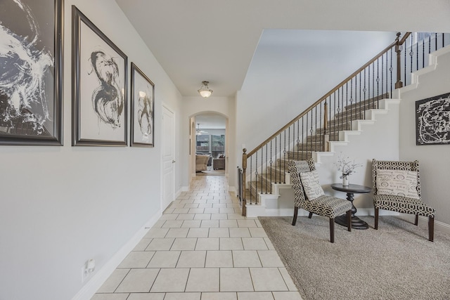 foyer entrance with stairs, arched walkways, baseboards, and tile patterned floors