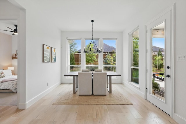 dining room featuring light wood-style floors, baseboards, and ceiling fan with notable chandelier