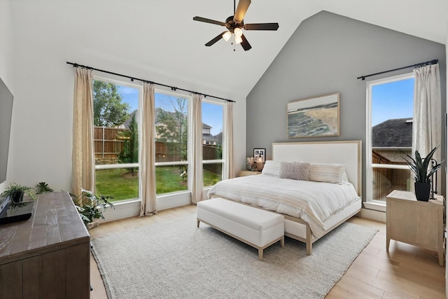 bedroom featuring high vaulted ceiling, multiple windows, light wood finished floors, and ceiling fan
