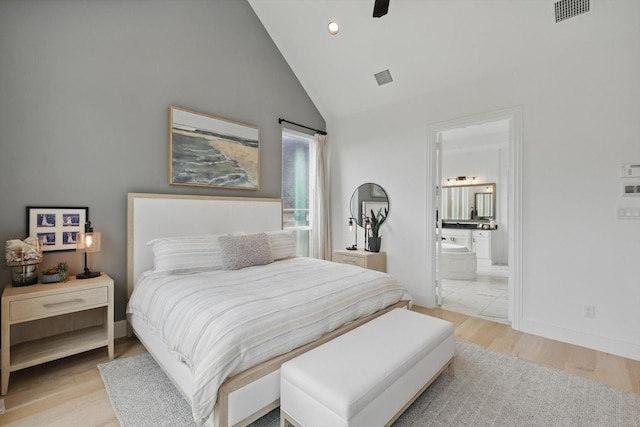 bedroom with high vaulted ceiling, ensuite bathroom, light wood finished floors, and visible vents