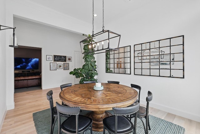 dining space with baseboards, an inviting chandelier, and light wood-type flooring