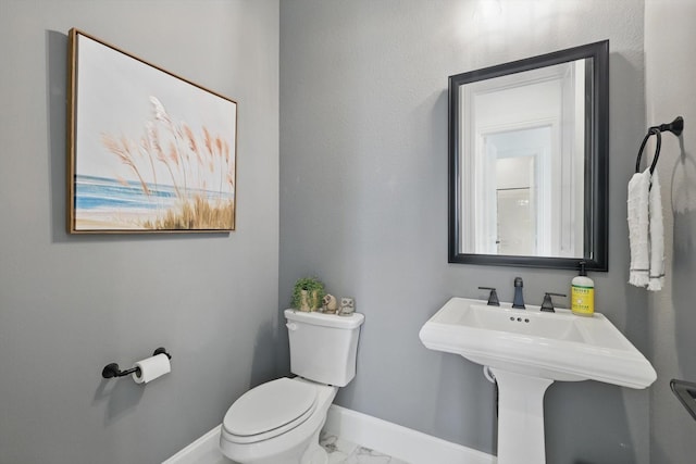 half bathroom with toilet, baseboards, and marble finish floor