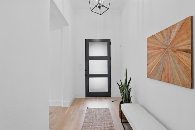 entryway featuring baseboards, a chandelier, ornamental molding, and wood finished floors