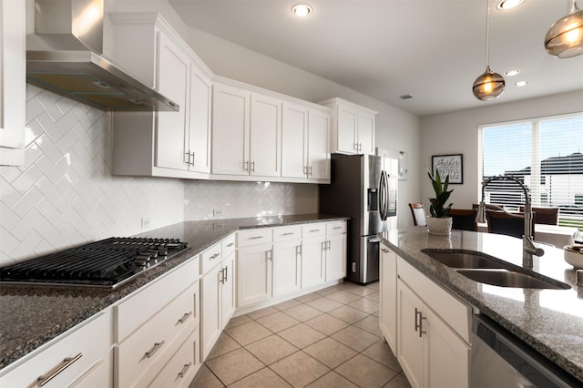 kitchen featuring white cabinets, wall chimney range hood, appliances with stainless steel finishes, and a sink