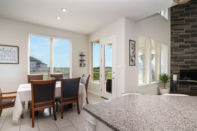 dining room with recessed lighting, a fireplace, baseboards, and light tile patterned floors