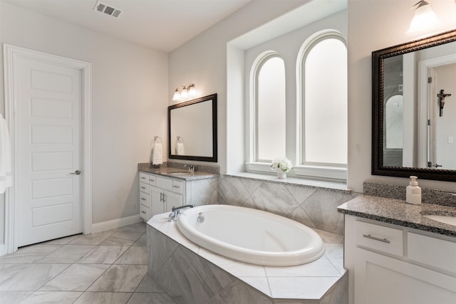 full bathroom with a garden tub, two vanities, visible vents, and a sink
