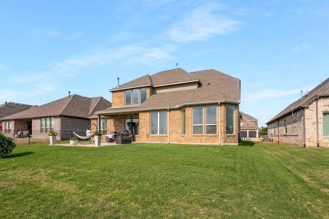 back of house featuring a lawn, fence, a patio area, and brick siding