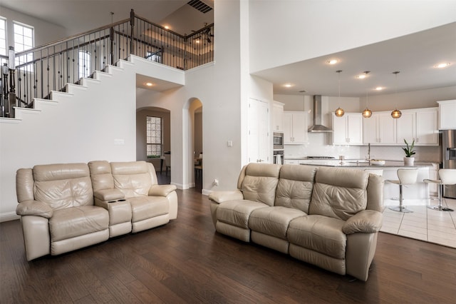 living room with baseboards, a high ceiling, arched walkways, and dark wood finished floors