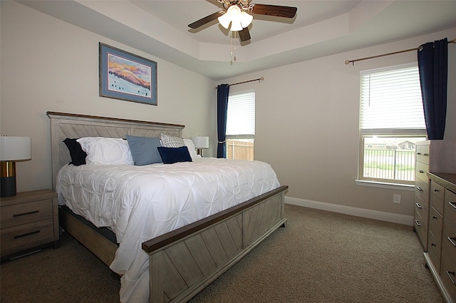 bedroom with a raised ceiling, baseboards, light colored carpet, and ceiling fan