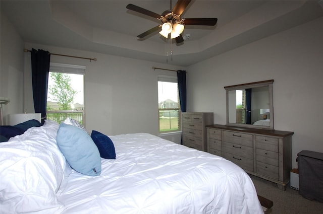 bedroom featuring light carpet, a ceiling fan, and a raised ceiling